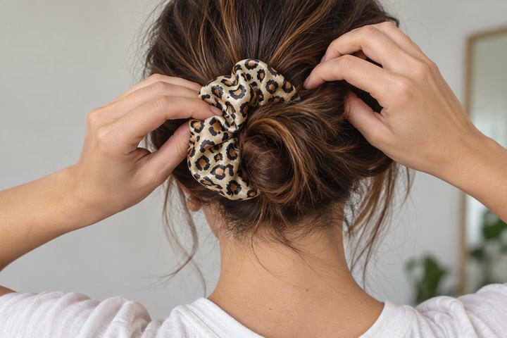 A loose daytime bun being gathered with a printed silk scrunchie.