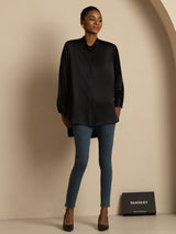 Woman wearing a black silk stand-collar blouse with button front and high-low hem