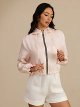 Woman wearing a black cropped silk hooded jacket with pockets