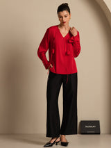 Woman in a navy silk V-neck blouse with long sleeves and 3D rose detail
